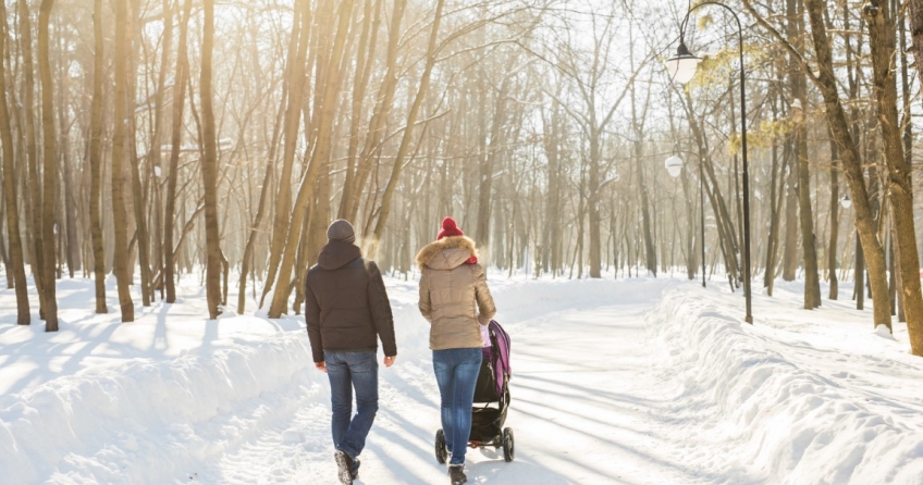 Junge Familie spaziert mit Kinderwagen